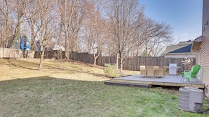A backyard with a wooden deck, a green chair, and an air conditioning unit. - Akron Home w/ Deck: Walk to Towpath Trail! (Akron)