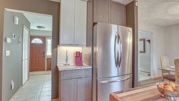 A modern kitchen with stainless steel appliances, wooden cabinets, and a wooden countertop with a bowl of fruit.