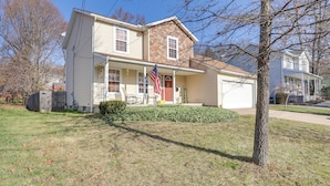 A two-story house with a garage, a front porch, and a small front yard. - Akron Home w/ Deck: Walk to Towpath Trail! (Akron)