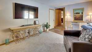 A living room with a flat-screen TV, a decorative console table, a sofa, and a painting on the wall. - Akron Home w/ Deck: Walk to Towpath Trail! (Akron)