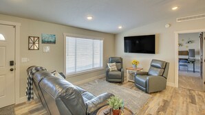 A living room with a leather couch, two armchairs, a flat-screen TV, and a dining area in the background. - Modern Bloomington Home ~ 10 Mi to Bear Lake! (Bloomington)