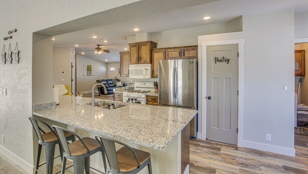 A spacious kitchen with granite countertops, stainless steel appliances, and a breakfast bar with bar stools. - Modern Bloomington Home ~ 10 Mi to Bear Lake! (Bloomington)