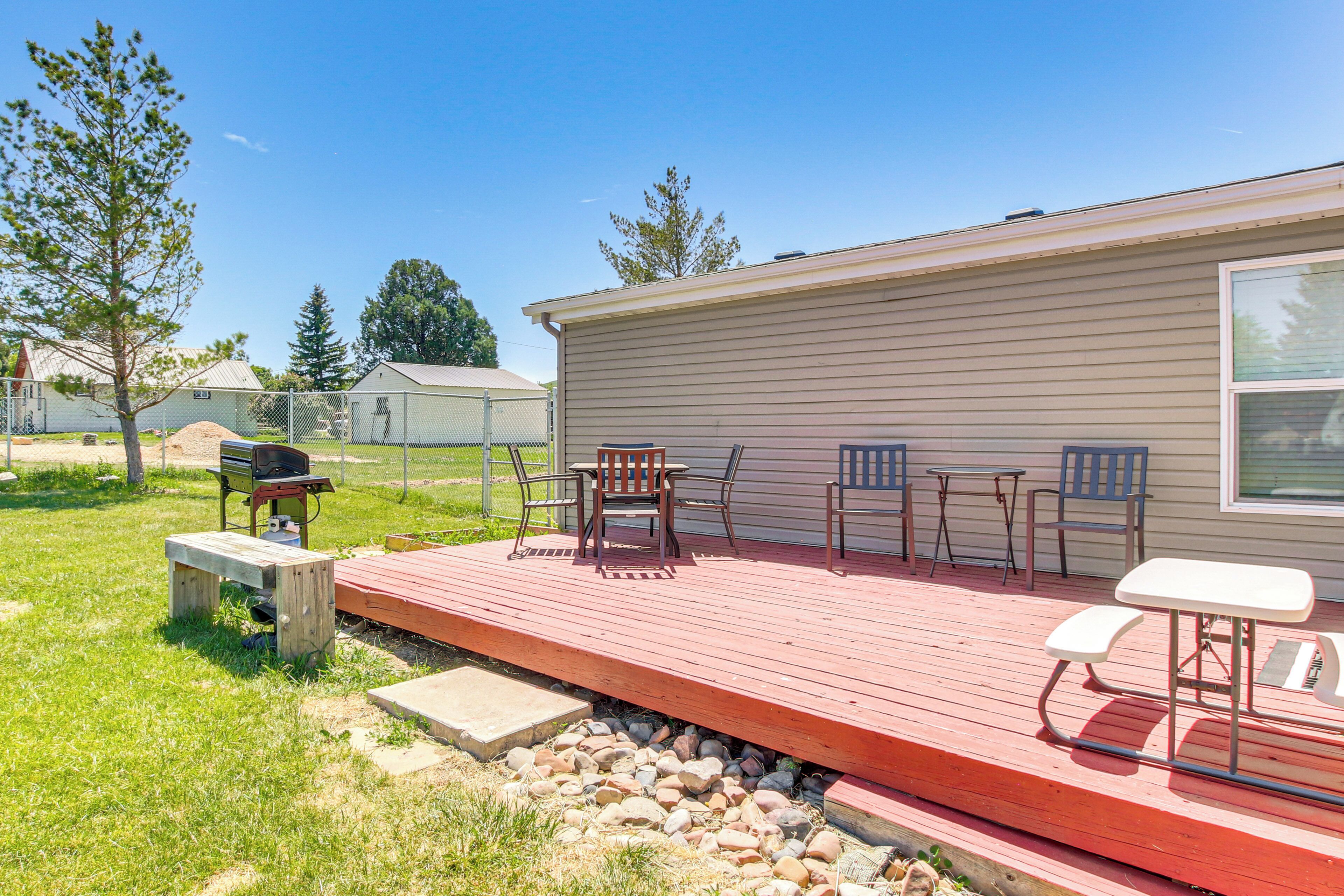 A covered outdoor deck with a grill, chairs, and a table.