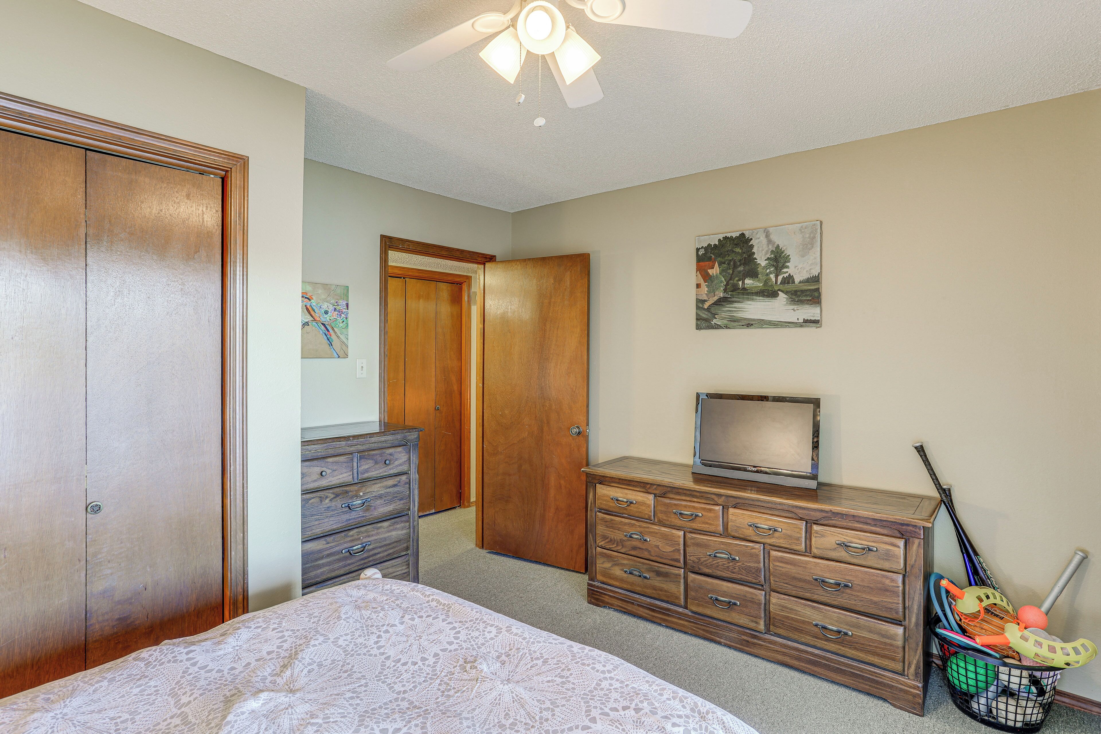Un dormitorio con cama, cómoda de madera, televisor y equipo deportivo.
