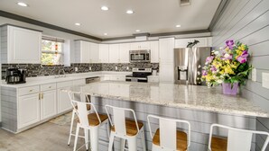 A modern kitchen with white cabinetry, granite countertops, and stainless steel appliances. - Front Row Beachfront Long Beach Getaway (Long Beach)