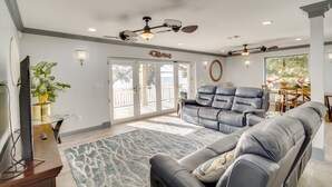 A spacious living room with a large leather sofa, a television, and a dining area with a table and chairs. - Front Row Beachfront Long Beach Getaway (Long Beach)