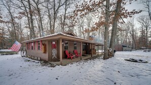 Uma cabana com varanda, cadeiras vermelhas e uma bandeira americana.