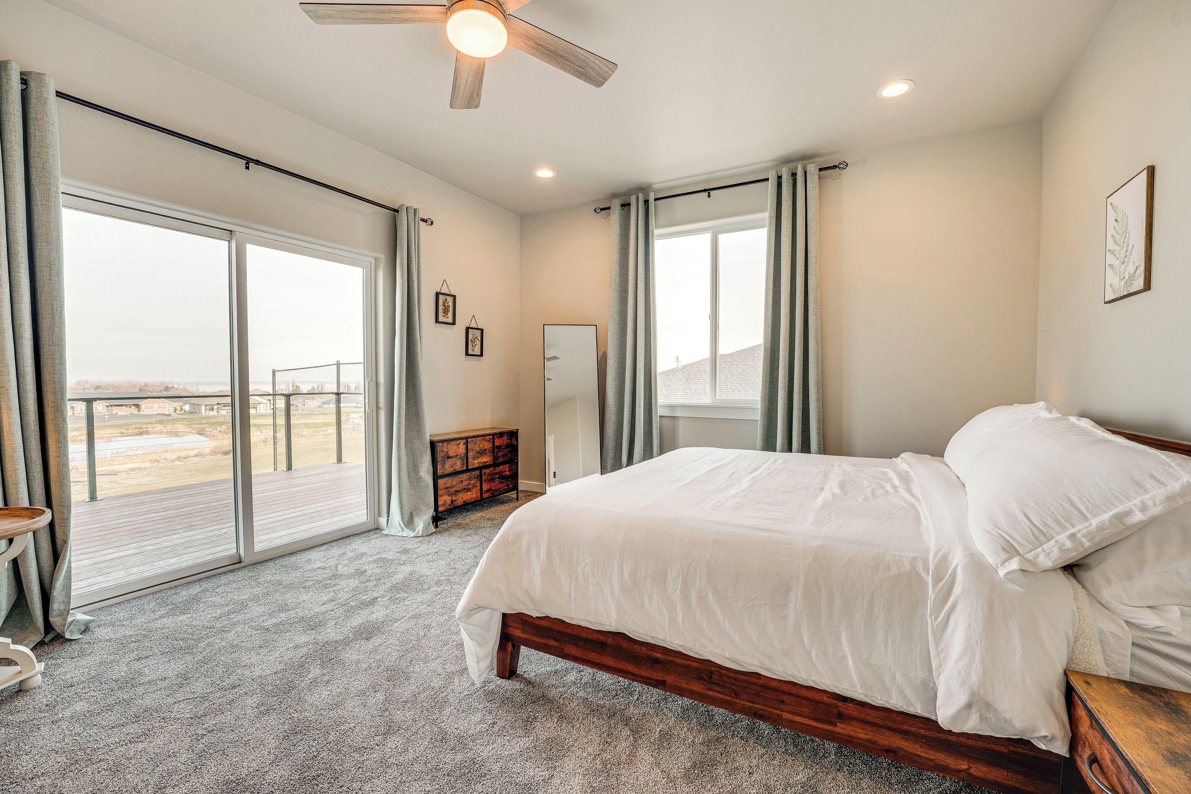 Un dormitorio con una cama grande, ventilador de techo y vistas a través de puertas correderas de cristal.