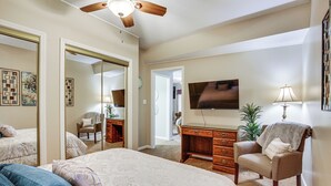 A bedroom with a large bed, a desk, a chair, a TV, and a ceiling fan. - 5 Mi to Fort Osage: Countryside Studio (Sibley)