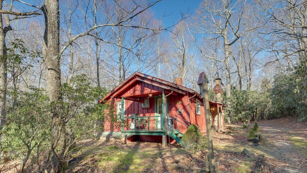 A red cabin with a green porch, surrounded by trees and a clear sky. - Dog-friendly Burnsville Cabin Rental Near Hiking! (Burnsville)