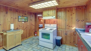 A wooden cabin kitchen with a stove, cabinets, and a tiled floor. - Dog-friendly Burnsville Cabin Rental Near Hiking! (Burnsville)