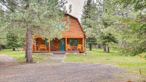 A log cabin with a porch and outdoor seating, surrounded by trees. - Peaceful Donnelly Retreat < 1 Mi to Lake Cascade! (Donnelly)