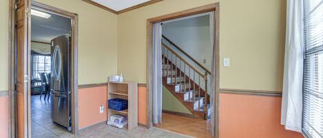Una habitación amplia con una escalera de madera, una estantería empotrada y un refrigerador.