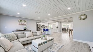 A spacious living room with a sectional sofa, a white coffee table, and a kitchen in the background. - Pool + Screened Lanai! Florida Gulf Coast Getaway (Rotonda West)