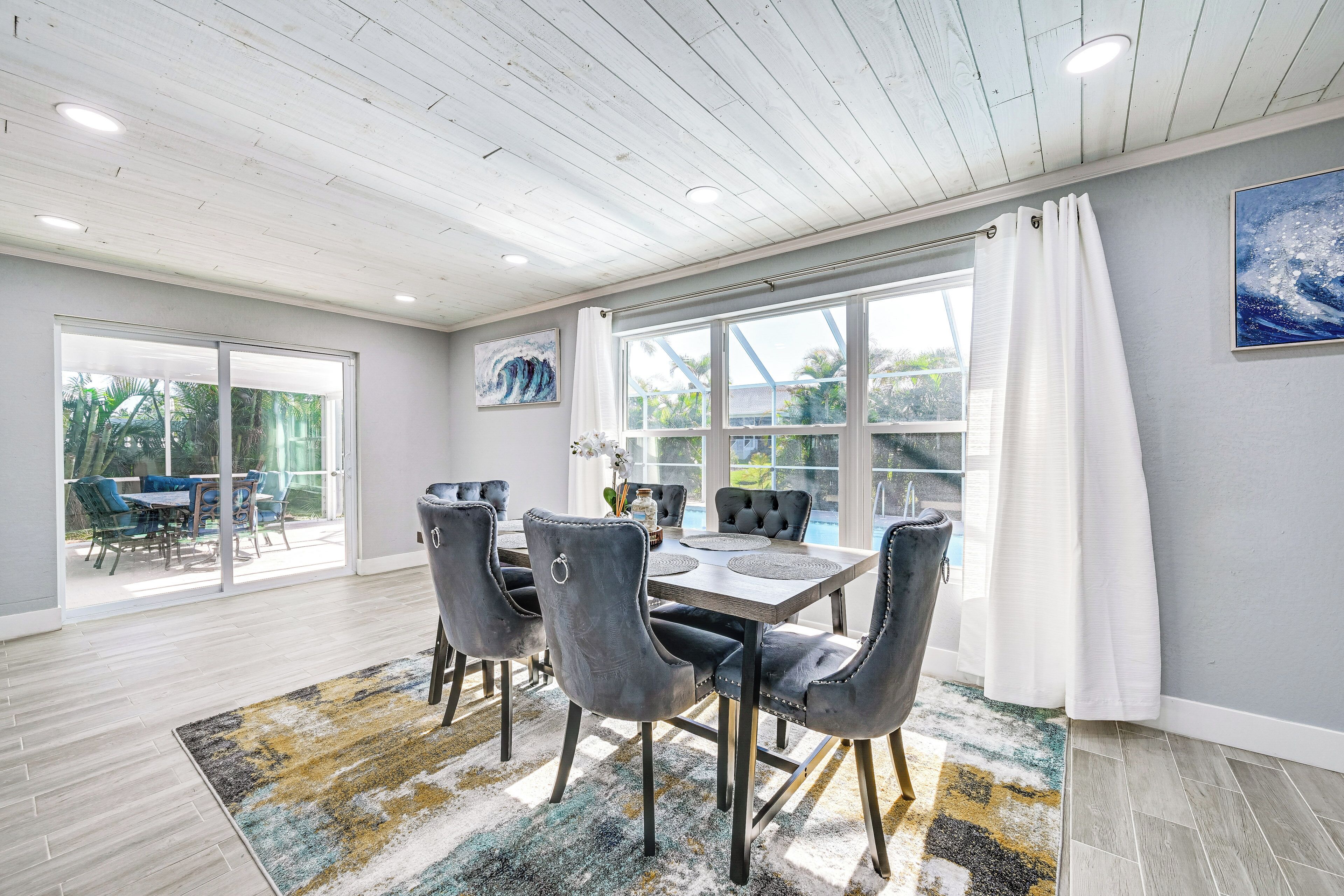 A dining area with a table and chairs, large windows, and a view of the outdoors.