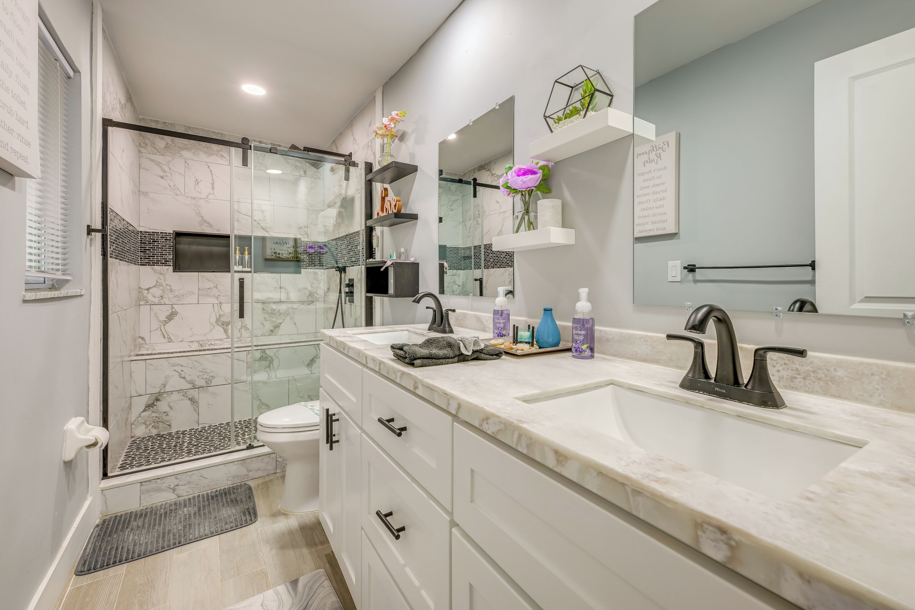 A modern bathroom with a glass-enclosed shower, a double sink vanity, and a large mirror.