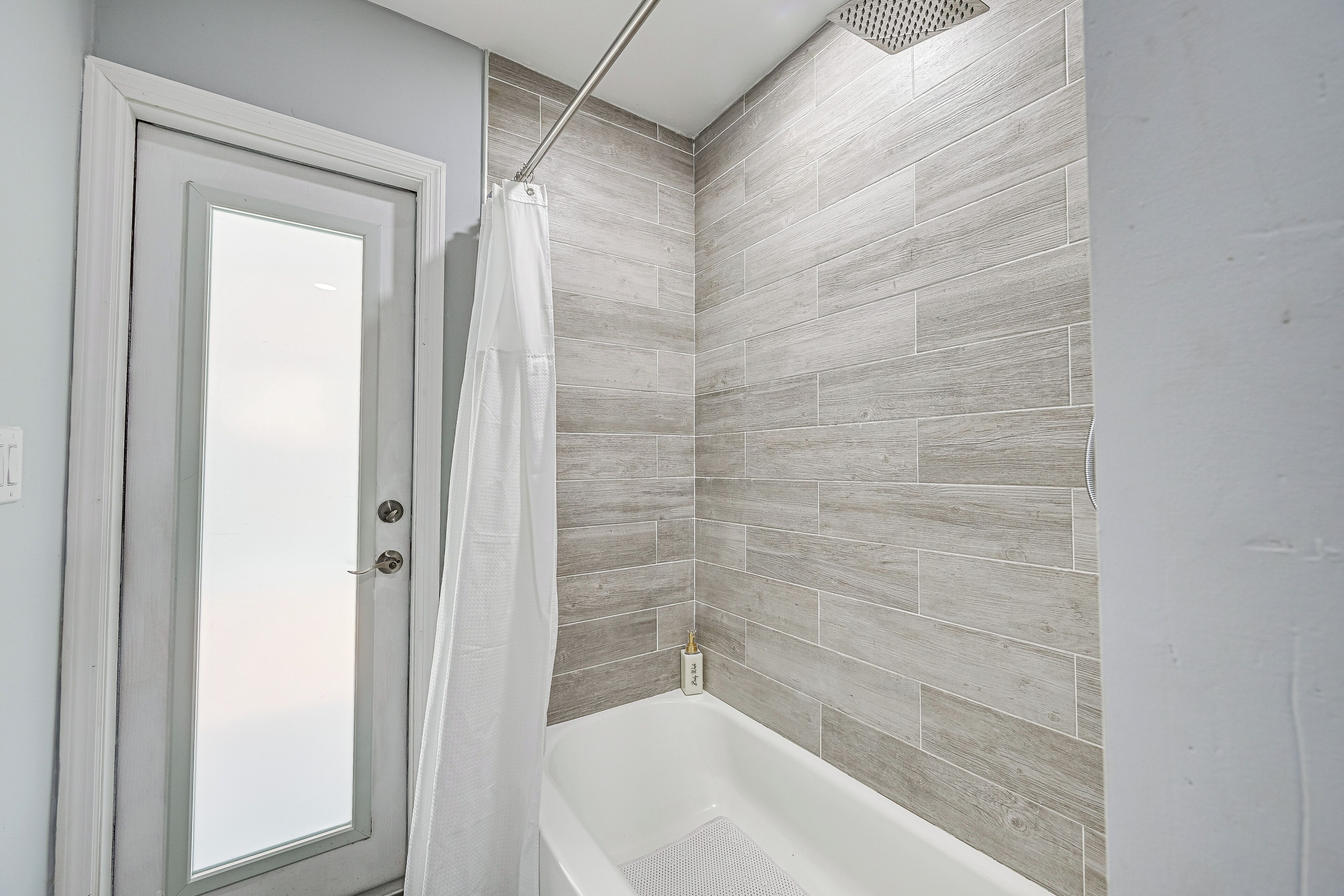 Une salle de bain avec une douche, une porte et un mur carrelé.