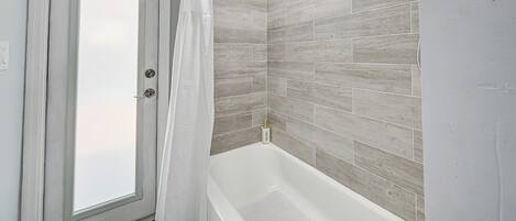 Une salle de bain avec une douche, une porte et un mur carrelé.