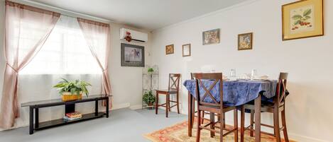 A dining area with a table set for four, surrounded by wooden chairs, a blue tablecloth, and a patterned rug.