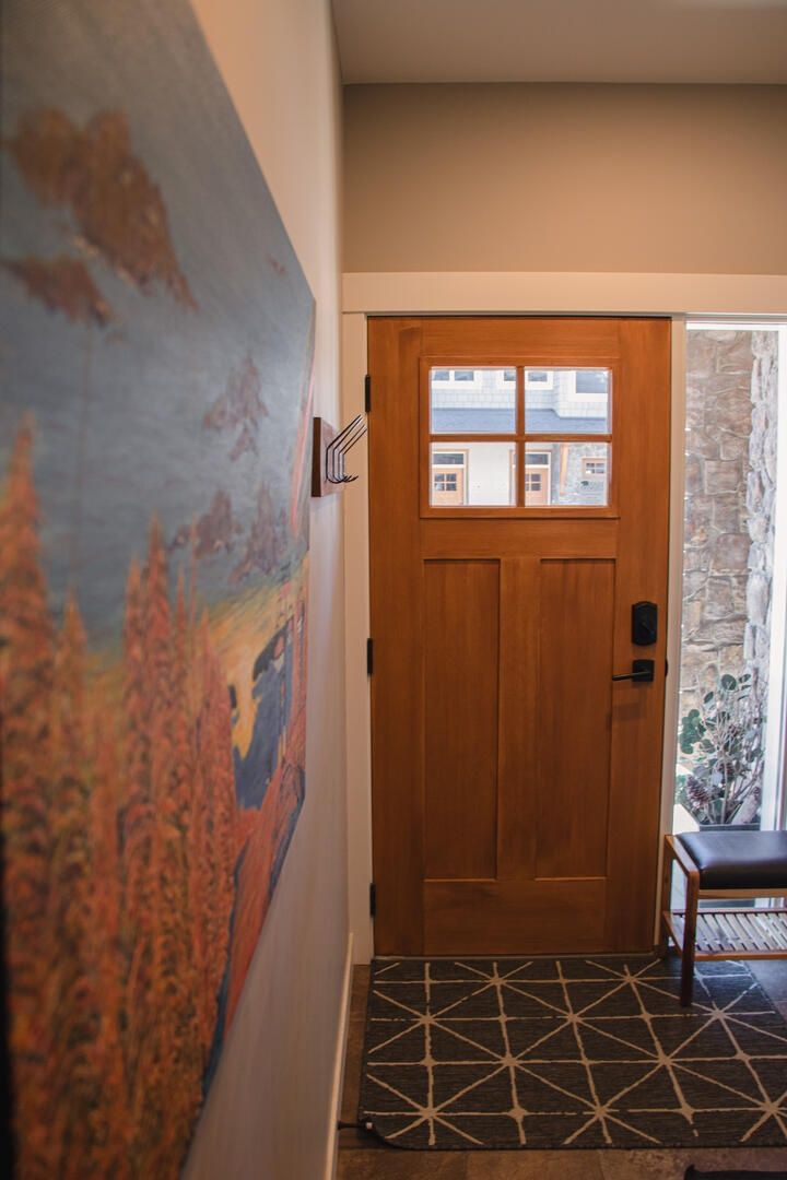 Una puerta de madera con un ventanal, una pared de piedra y un piso de baldosas.