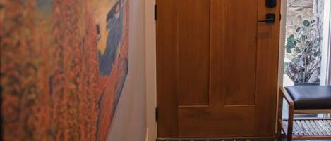 Una puerta de madera con un ventanal, una pared de piedra y un piso de baldosas.