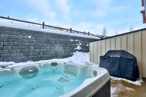 A hot tub with a wooden fence and a grill in the background. - Echo Landing #20 3 Bedroom Townhouse (Sun Peaks)