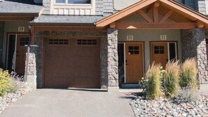 A multi-story residential building with a stone facade, multiple garage doors, and a clear sky.