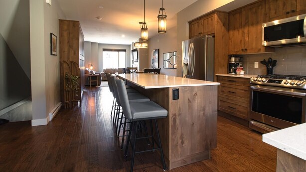 A modern kitchen with wooden cabinets, stainless steel appliances, and a central island with bar stools.