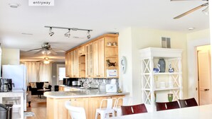 Una cocina moderna con armarios de madera, una isla blanca y un comedor con sillas blancas.