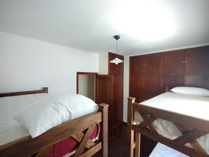 Una habitación con dos camas literas de madera, un armario de madera y una lámpara colgante.