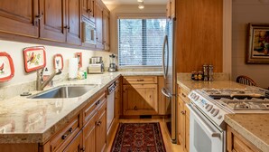 A kitchen with wooden cabinets, a double sink, a stove, and a refrigerator. - Dollar Meadows Condo 1362- Room for the Whole Family at Sun Valley Resort! (Sun Valley)