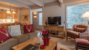 A cozy living room with a sofa, coffee table, and a TV. There's a dining area with wooden cabinets and a chandelier. - Dollar Meadows Condo 1362- Room for the Whole Family at Sun Valley Resort! (Sun Valley)