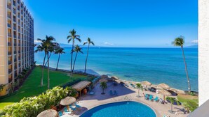 A hotel with a pool, lounge chairs, and a view of the ocean.
