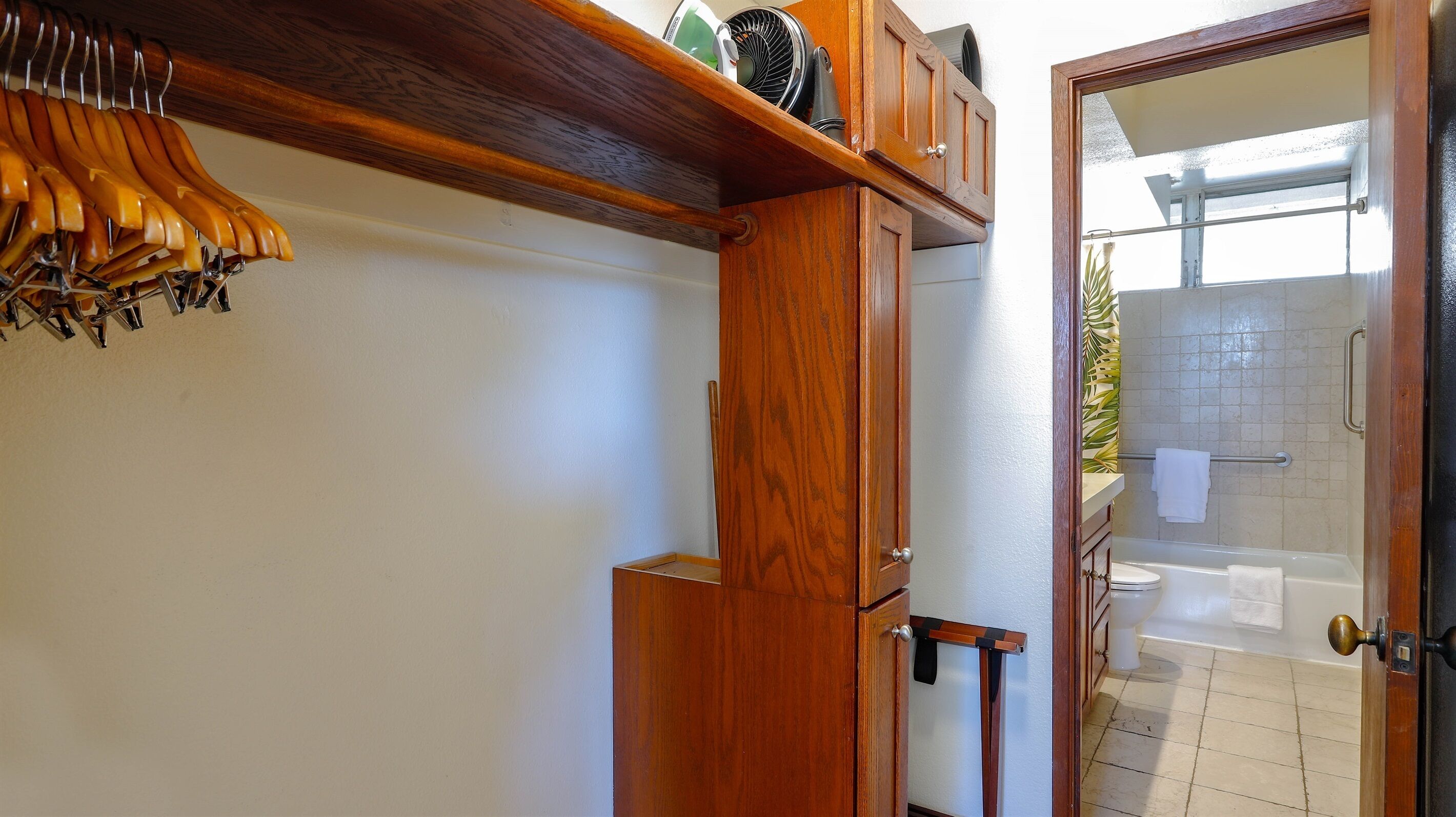 A bathroom with a wooden door, a towel rack, and a shower area.