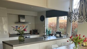 Eine moderne Küche mit einer zentralen Kochinsel, weißen Schränken und einem Essbereich mit einem Holztisch.