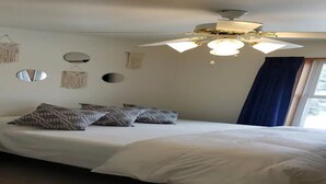 Un dormitorio con cama, ventilador de techo y decoración en las paredes.