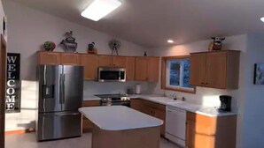 Una cocina moderna con armarios de madera, electrodomésticos de acero inoxidable y una isla central.