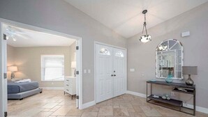 A bedroom with a bed, dresser, and a console table with decorative items.
