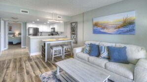 A modern living room with a sofa, coffee table, and a painting of a beach scene. - HS-1129 Spacious 2-bedroom condo in Myrtle Beach (Myrtle Beach)