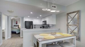 A modern kitchen with white cabinets, a central island with stools, and a dining table. - HS-1129 Spacious 2-bedroom condo in Myrtle Beach (Myrtle Beach)