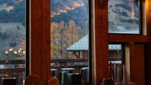 A cozy room with large windows, wooden beams, and a view of mountains. - Ferme du Cugnon (Les Contamines-Montjoie)