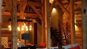 A cozy interior with a wooden ceiling, a sofa with cushions, and a coffee table with books. - Ferme du Cugnon (Les Contamines-Montjoie)