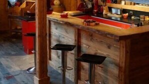 A rustic wooden interior with a bar area, stools, and a large window. - Ferme du Cugnon (Les Contamines-Montjoie)