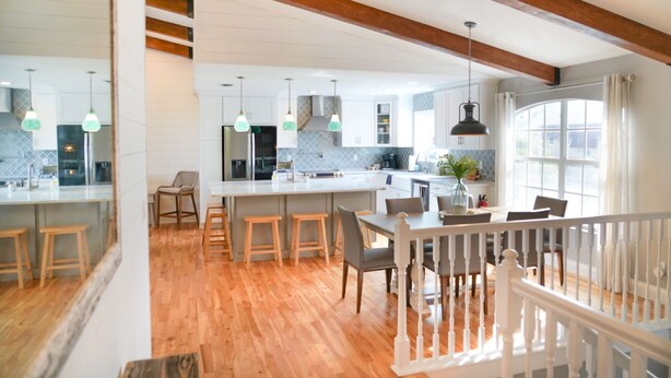 Une cuisine spacieuse avec des poutres en bois, un grand îlot central et des luminaires suspendus.