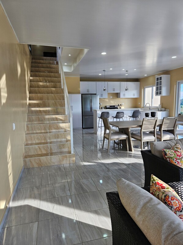 A modern kitchen with white cabinets, a central island, and a dining area with chairs and a table.