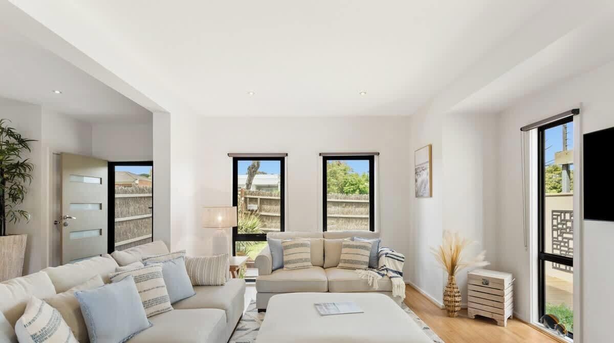 A spacious bedroom with a large bed, a sofa, and a window with a view of greenery.