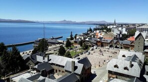 Uma vila costeira com edifícios históricos, uma praça central e um cais.