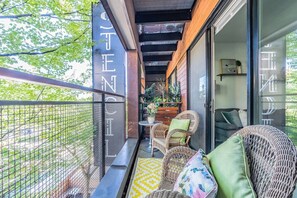 Ein Balkon mit Korbmöbeln, einem kleinen Tisch und einem Blumentopf.