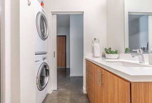 Un baño moderno con lavamanos, espejo y una planta pequeña.