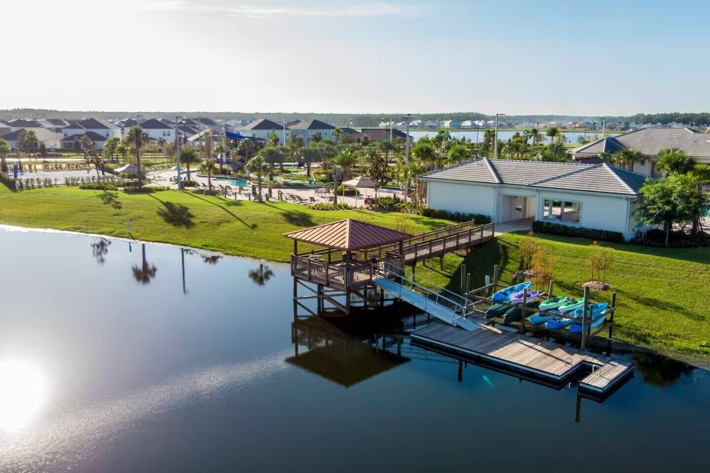 A residential area with a dock, a small pavilion, and houses in the background.